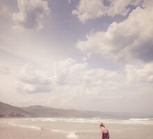 Girl Walking Along a Beach by jamjarphotos