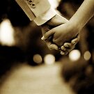 Bride and groom holding hands sepia toned black and white silver gelatin 35mm film analog wedding photograph by edwardolive