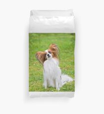Portrait of a papillon purebreed dog sitting on the grass Duvet Cover